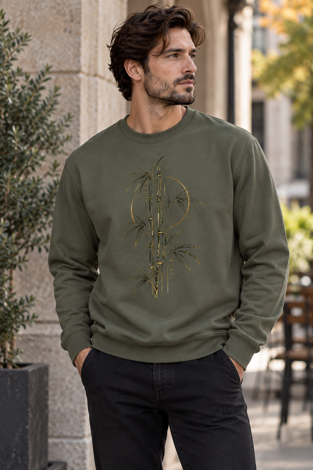 Men wearing a Olive green unisex graphic sweatshirt featuring a stylized bamboo botanical design with fine dark lines and golden accents by Exalyn Studio.