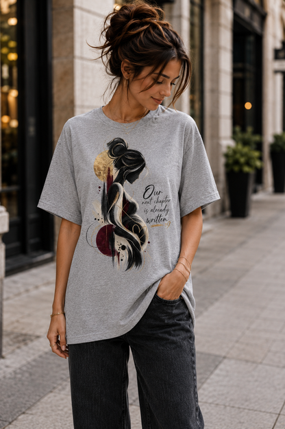 Grey women’s pregnancy announcement graphic T-shirt with an artistic expectant mother silhouette in black, burgundy and gold and the message Our next chapter is already written.