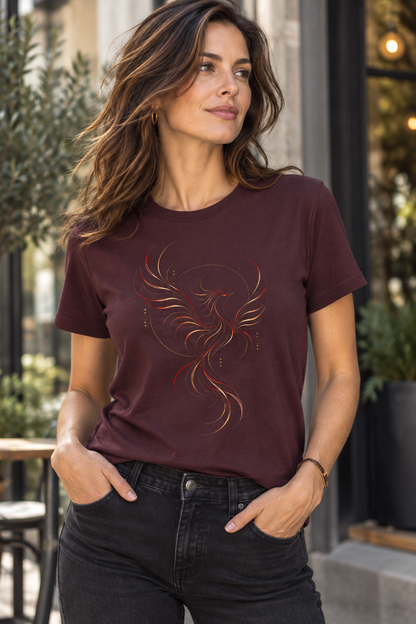 A woman wearing a Burgundy graphic T-shirt featuring the Crimson Phoenix design with a flowing phoenix-inspired bird in crimson, gold and dark curved linework.